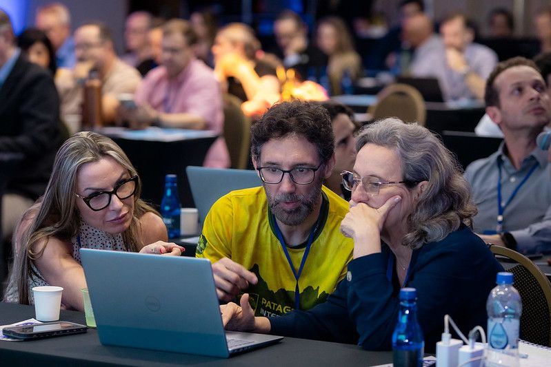 Grupo trabalhando lado a lado no notebook durante um Hackathon de Implementação
